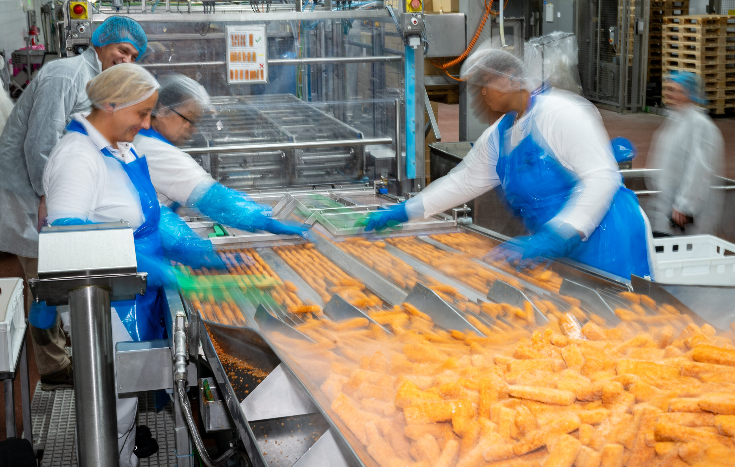 Personen arbeiten an einem Fließband.