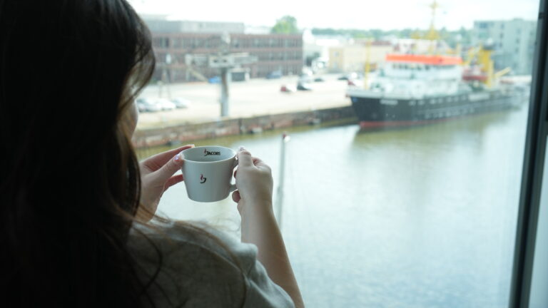 Person hält Kaffeetasse am Fenster