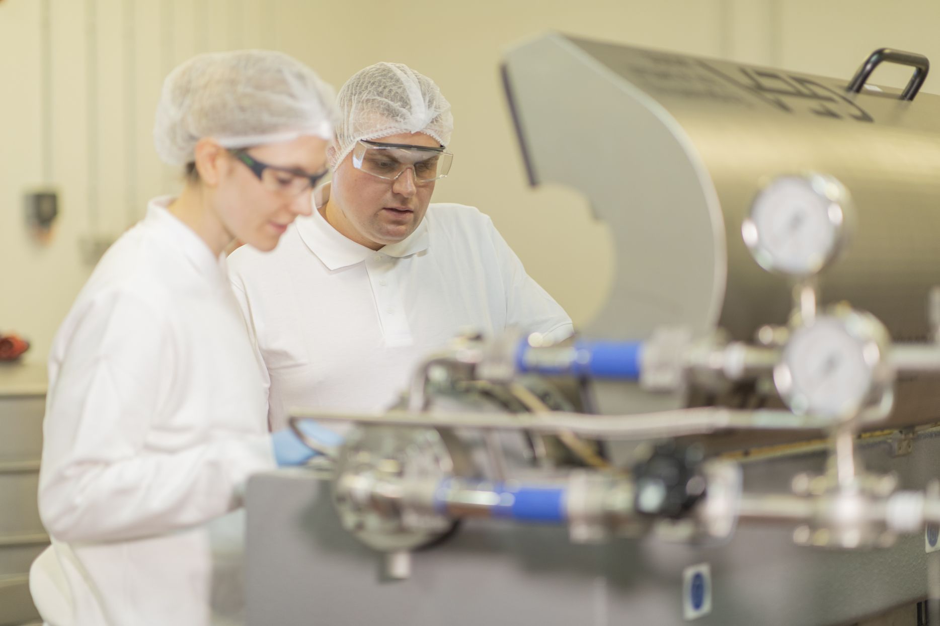 Frida Köning und Magnus Rienäcker überprüfen eine Membran innerhalb einer Lebensmittelanlage. Es geht um Proteinforschung.