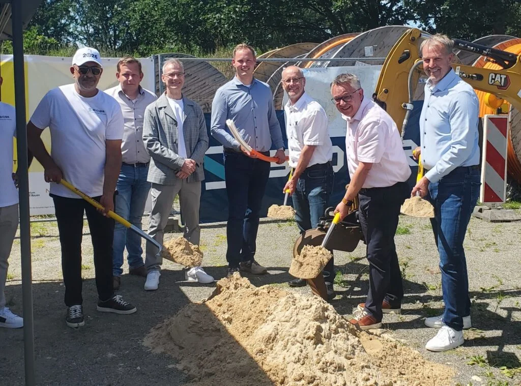 Neben einem Mitarbeiter des Generalunternehmers Sidar (von links) stehen beim symbolischen Spatenstich Benjamin Kuss (Aconium GmbH), Dr. Dominik Mayer (Niedersächsisches Ministerium für Wirtschaft, Verkehr und Bauen), Denis Ebbing (Muenet), Ralf Bruns (Landkreis Cuxhaven) und die Bürgermeister Andreas Wittenberg.(Gemeinde Hagen im Bremischen) sowie Guido Dieckmann (Gemeinde Beverstedt).
