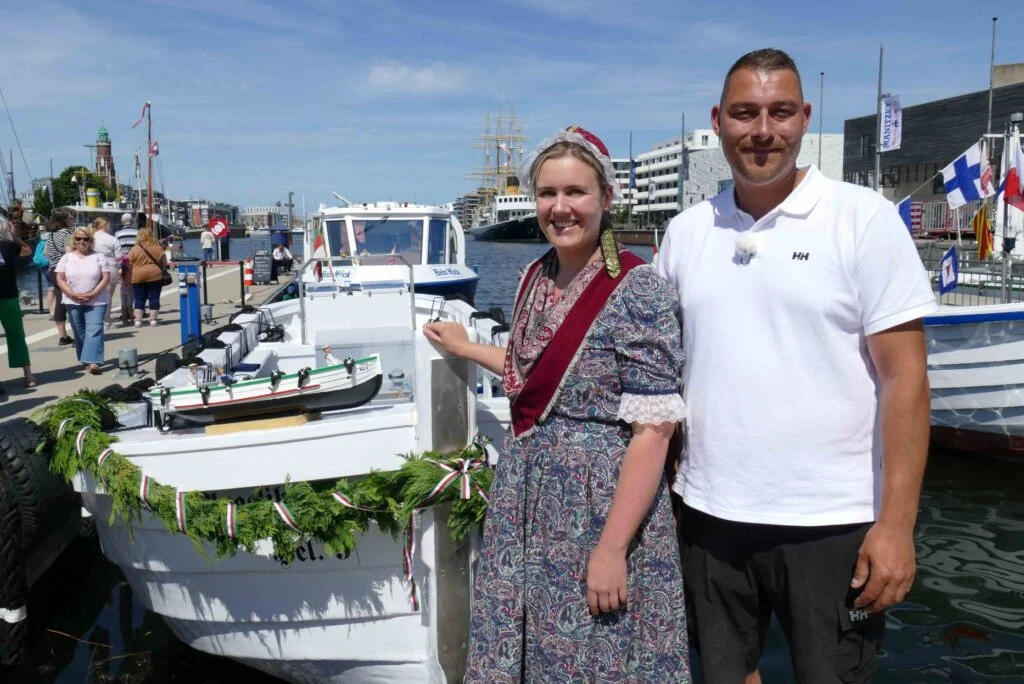 Kapitän Christian Schwan und Taufpatin Tamara Schwiemann stehen vor der „Angelika“, dem ältesten bekannten noch aktiven Helgoländer Börteboot (Baujahr 1949), das im Neuen Hafen in Bremerhaven getauft wurde.