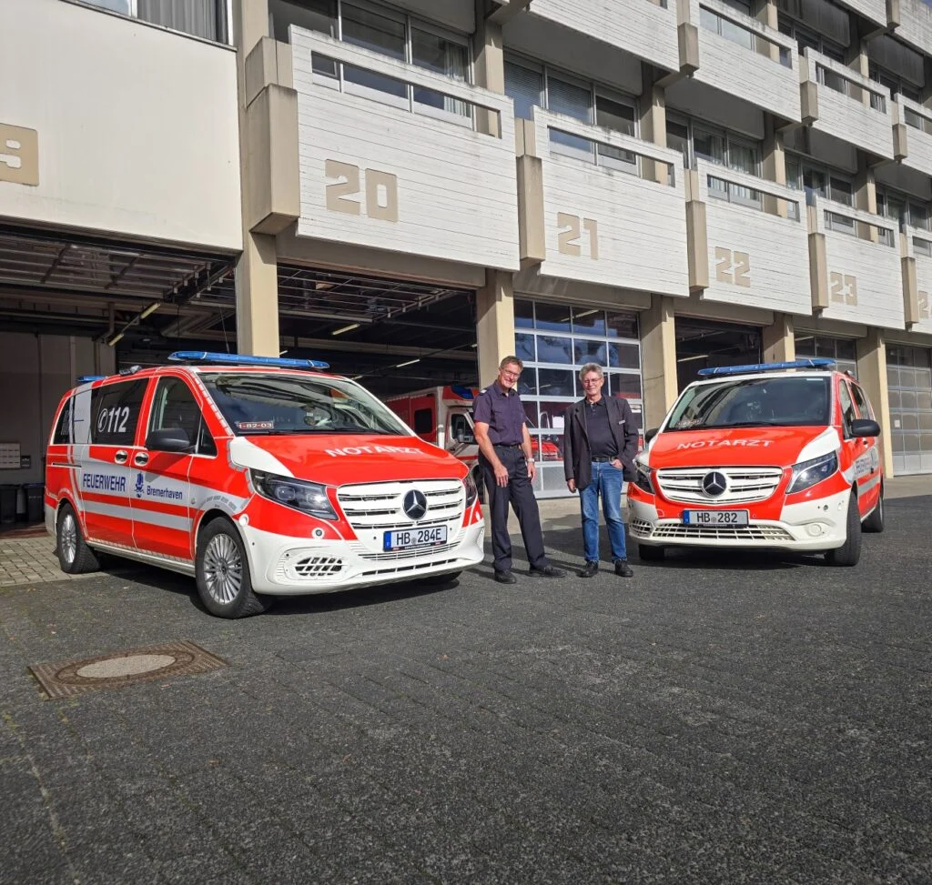 Nach den ersten Wochen im Einsatzbetrieb informierte sich Feuerwehrdezernent Stadtrat Peter Skusa (rechts) bei Rainer Suhrhoff, Teamleiter für Technische Dienste und Beschaffung, über die bisherigen Erfahrungen mit dem Fahrzeug. Links: das eNEF und rechts eines der NEF mit Verbrennungsmotor.